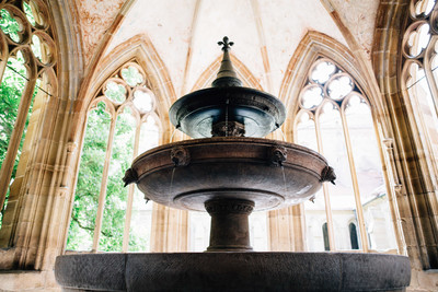 Ein dreistöckiger Brunnen steht unter dem Dach mit gotisch anmutenden Säulen.